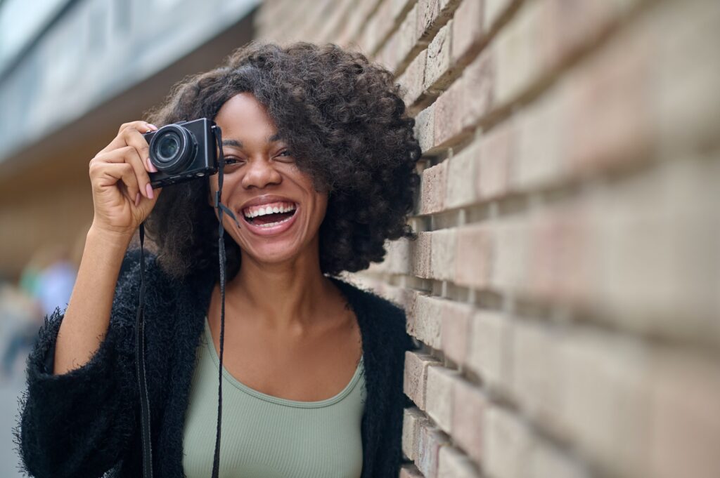 Pretty young female photographer smiling positively